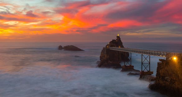 photo of the rock of the Virgin (Rocher de la Vierge) on dramatical sunset over Atlantic Ocean in Biarritz, France.
