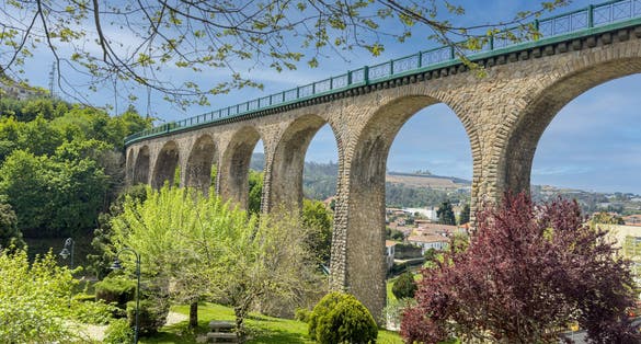 Photo of Old railway bridge and garden in Vouzela, Viseu, Portugal, on a sunny afternoon.