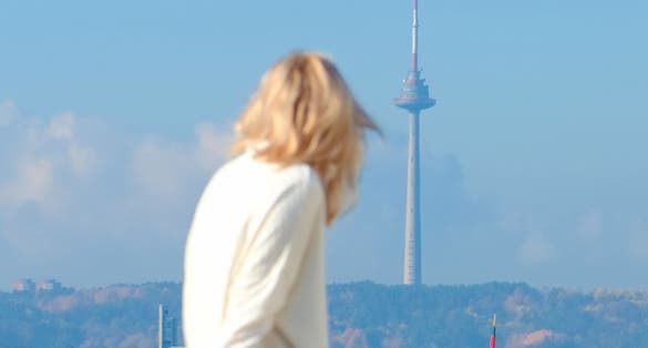 photo of girl out of focus looks at the Vilnius panorama with the TV tower and the gediminas castle in the background.