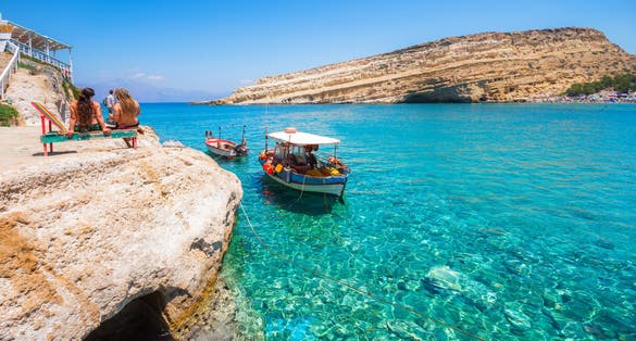 photo of view of Matala beach with small fishing boats and cave ,Mátala Greece.s on the rocks that were used as a roman cemetery and at the decade of 70's were living hippies from all over the world, Crete, Greece,