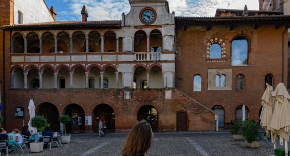 Girl looks at Palazzo Broletto in Piazza della vittoria in Pavia, Lombardy, Italy