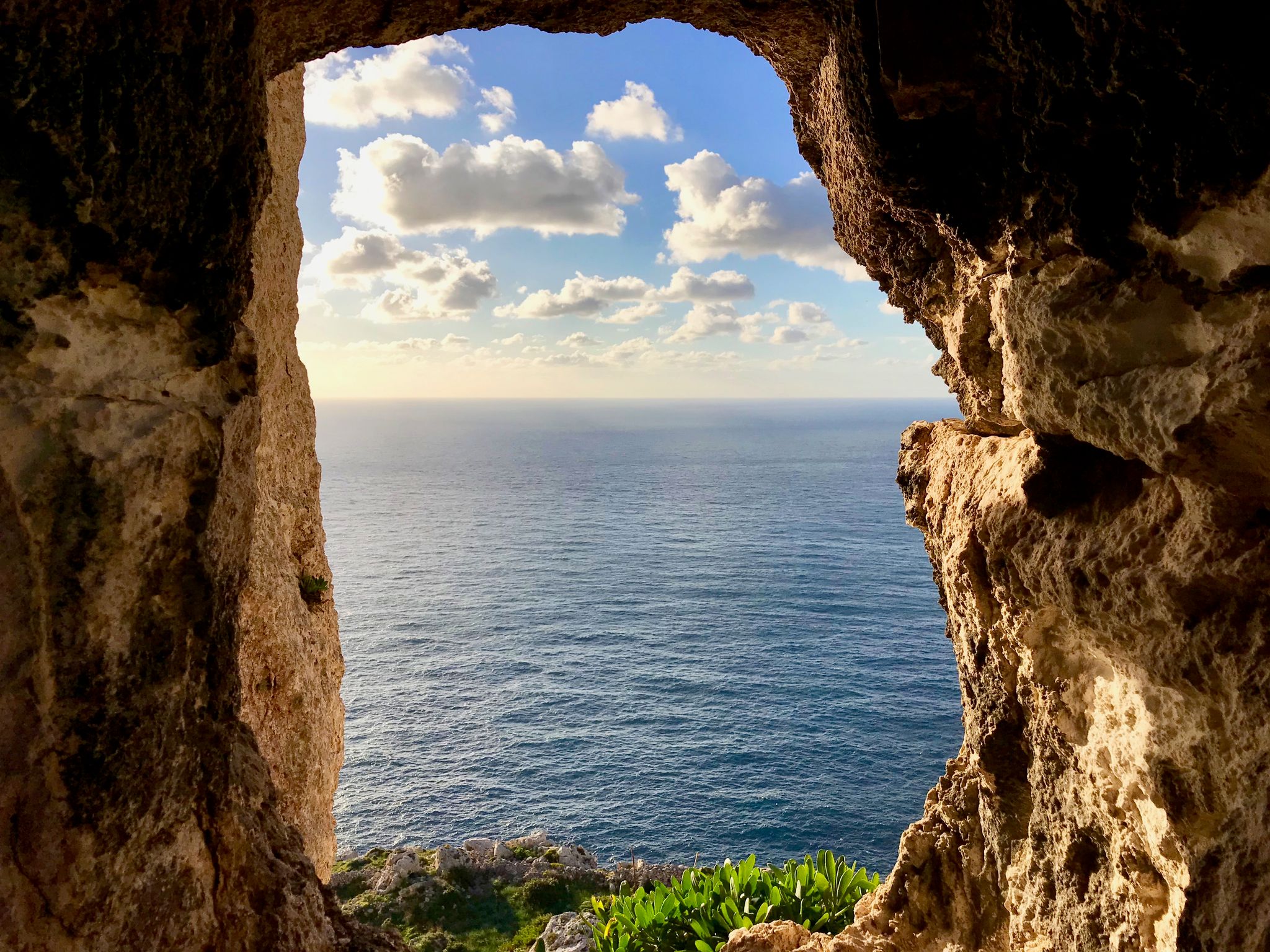 Photo of sunset and sea seen through a rocky window from Dingli Cliffs, Malta.