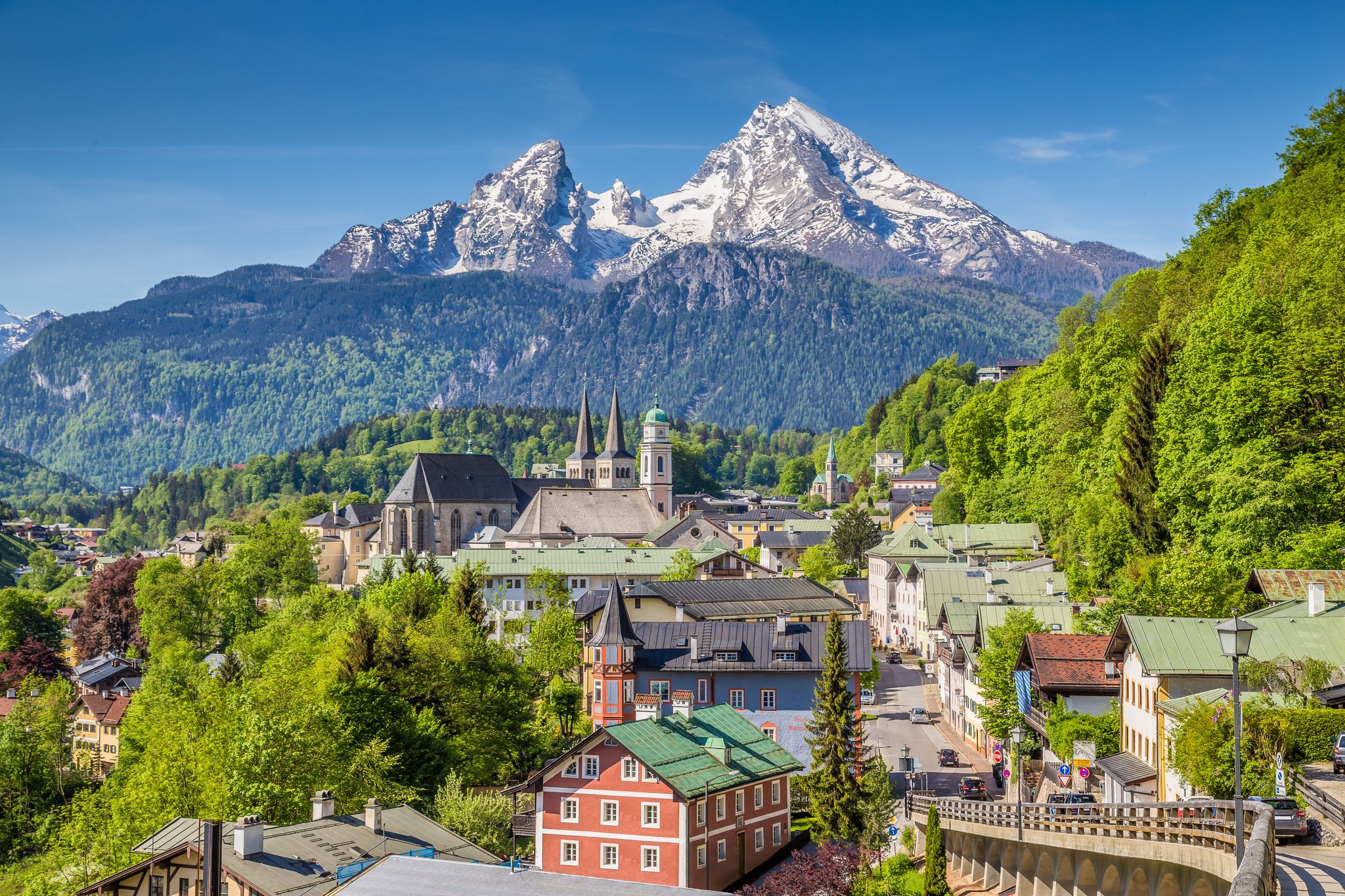 photo of historic town of Berchtesgaden with famous Watzmann mountain in the background on a sunny day with blue sky and clouds in springtime, National Park Berchtesgaden Land, Upper Bavaria, Germany.