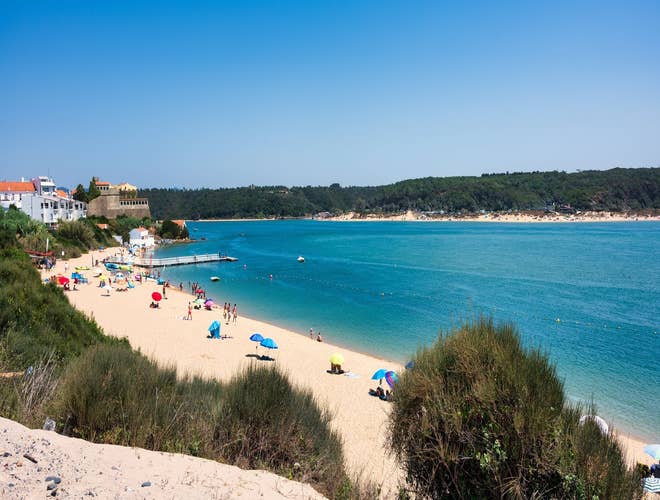 Beachgoers relax on the sandy shore of Porto Covo, a peaceful coastal gem in Portugal in August..jpg