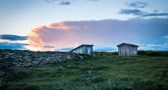 photo of view of Two old houses and a stone wall at sunset in Storwartz, just outside of Røros (Roros), Norway.