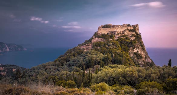 photo of view of Fortress Angelokastro on mountain at sunset. Corfu, Greece..