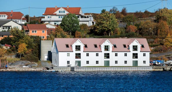 photo of view of Coastal Norwegian town landscape view with white wooden barn and houses on a background. Kristiansund, Norway.