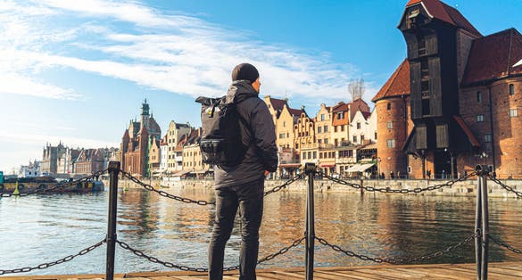 Photo of male tourist with a backpack in sunny winter in the old town of Gdansk, Poland.
