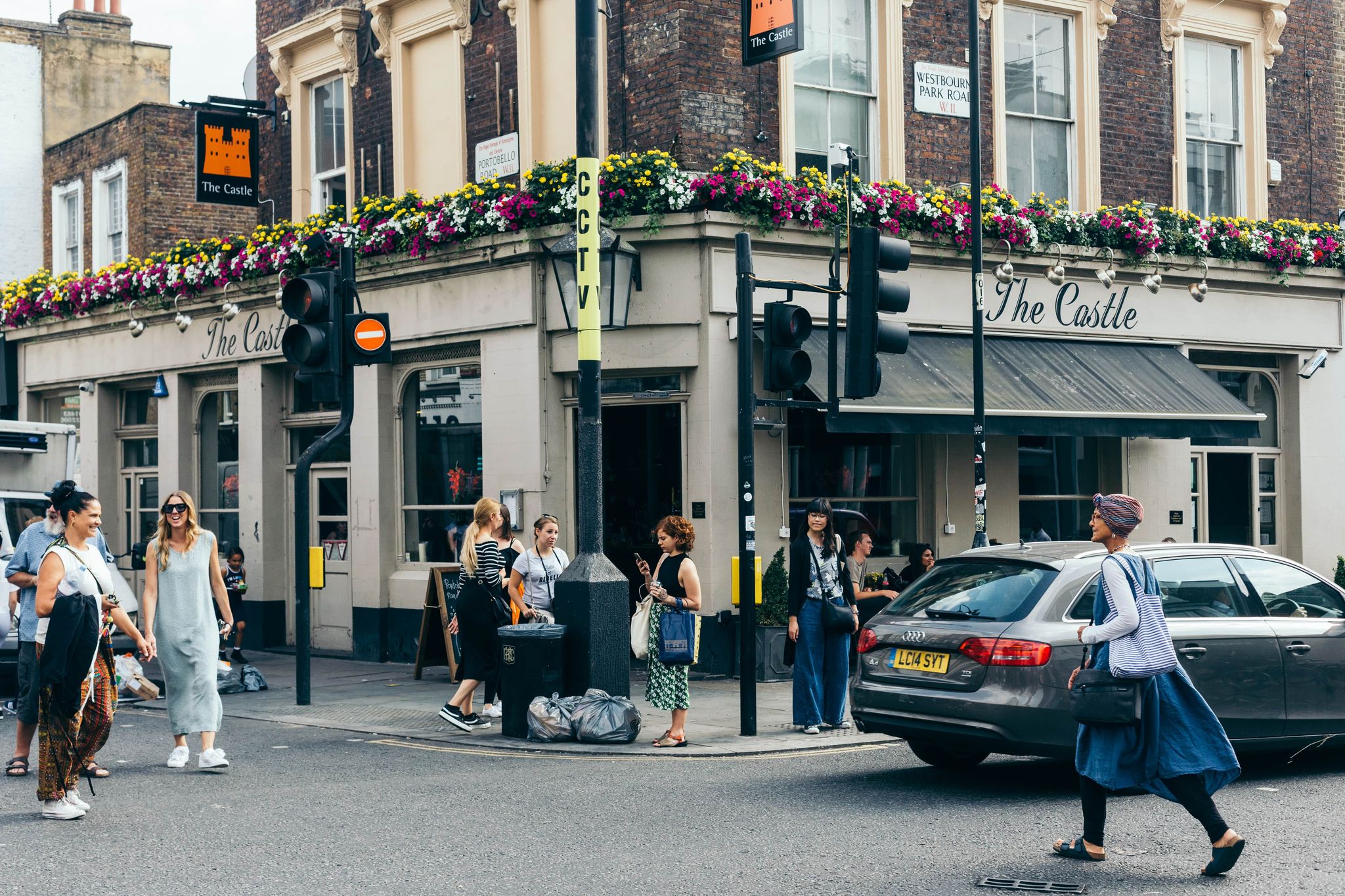 People walking past The Castle pub near Portobello Road in Notting Hill, London in summer..jpg