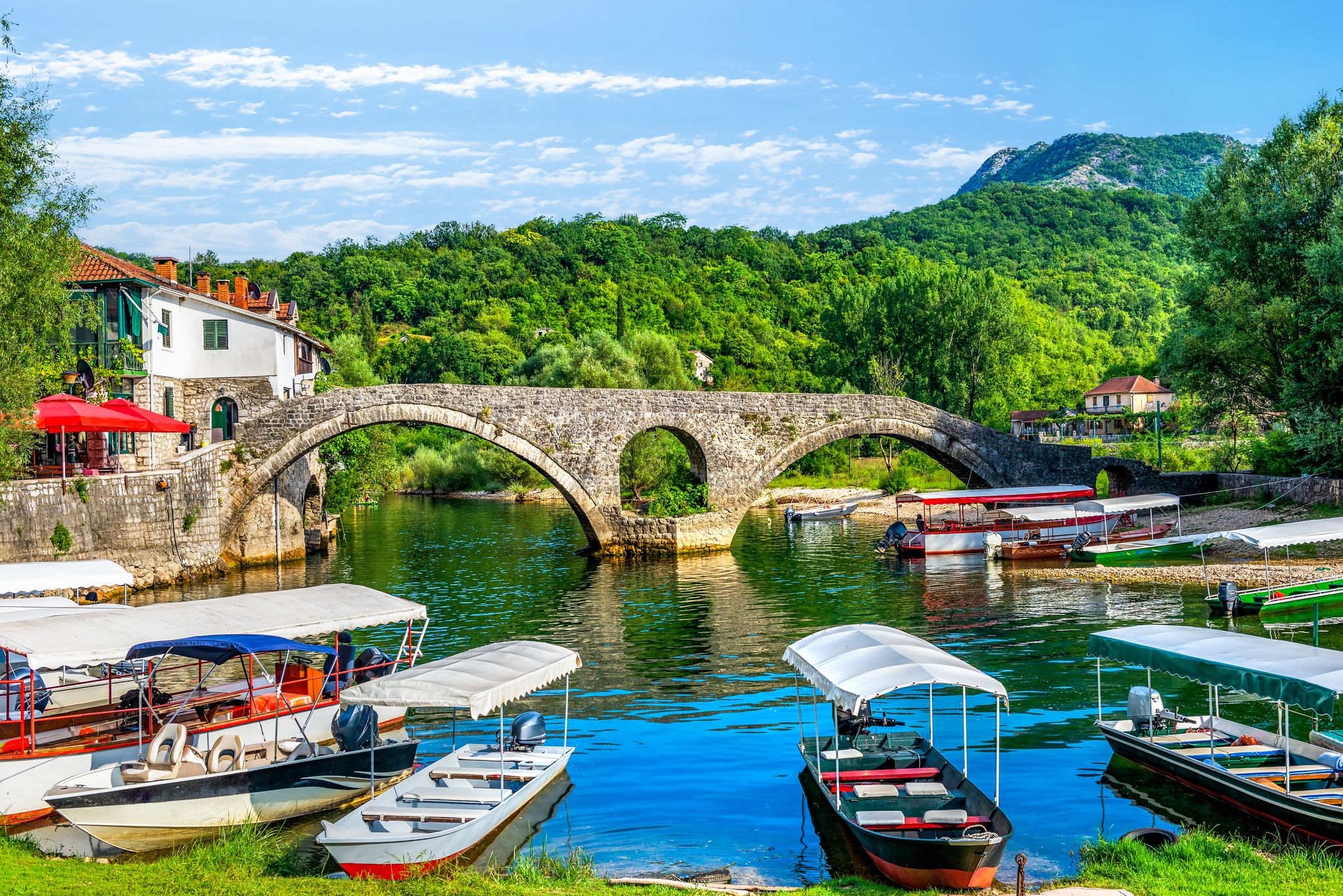 Photo of boats in front of Rijeka Crnojevića bridge on Crnojevica river in Montenegro.