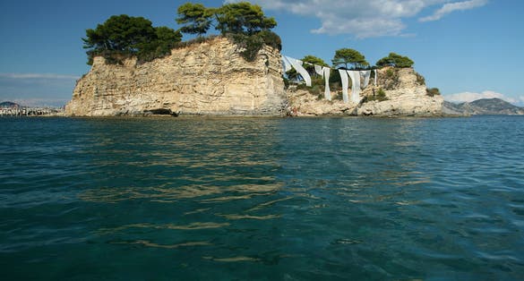 photo of view of Cameo Island, the most picturesque place in Laganas Bay, with pine trees growin Greece.g in the rocks and white cloth blowing in the wind, Agios Sostis, Zakynthos, Greece,Laganas 