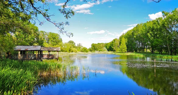 Photo of Small cabin near beautiful lake that reflects the blue sky, beautiful landscape near Craiova, Romania.