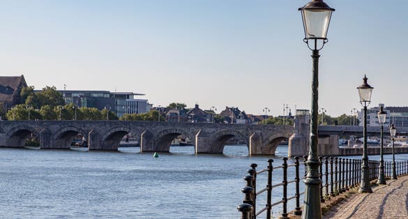 photo of selective focus of light pole along the river Maas with blurred view of the Saint Servatius bridge in Maastricht, Netherlands.