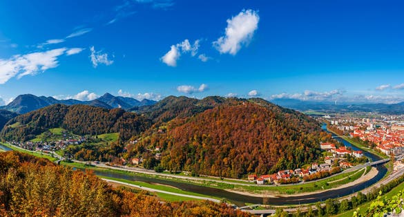 Aerial panoramic autumn view to the city Celje in Slovenia. Autumn trees, green meadows and red roofs. Outdoor travel background.