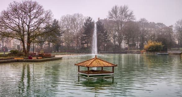 photo of the public parc de merl in luxembourgh city, Luxembourg, taken in spring 2018. It features a lake where a fountain is flowing and a hutch for ducks to have shelter.