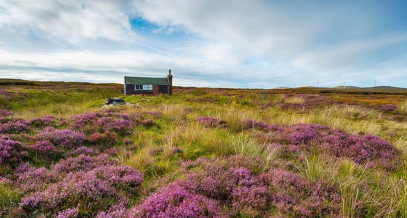 photo of a Scottish shieling hut on peat bog near Stornoway on the Isle of Lewis in the Outer Hebrides.