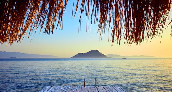 Photo of Bungalow on the sea at sunset. Wooden pavilions on the shore of a sandy beach, Bodrum, Turkey