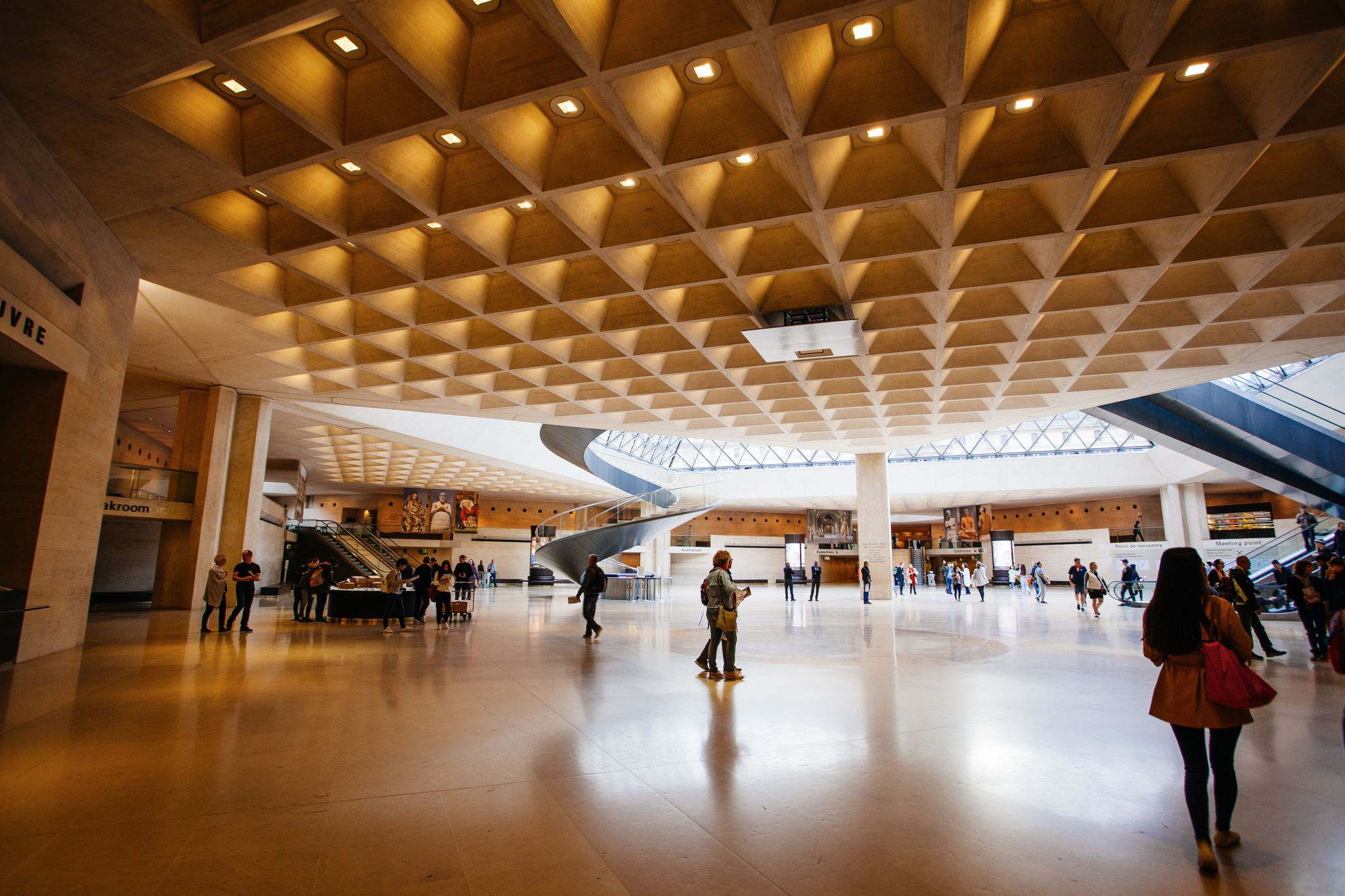 Photo of entrance to the Louvre. Visitors in the lobby under a glass pyramid, Paris, France.