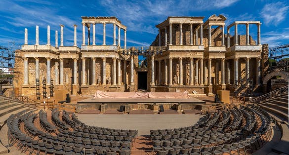 photo of view of Mérida Roman theater from behind with a view of the chairs, granite steps and the stage scaenae frons of classical Roman columns and statues for the Merida International Classical Theater Festival.