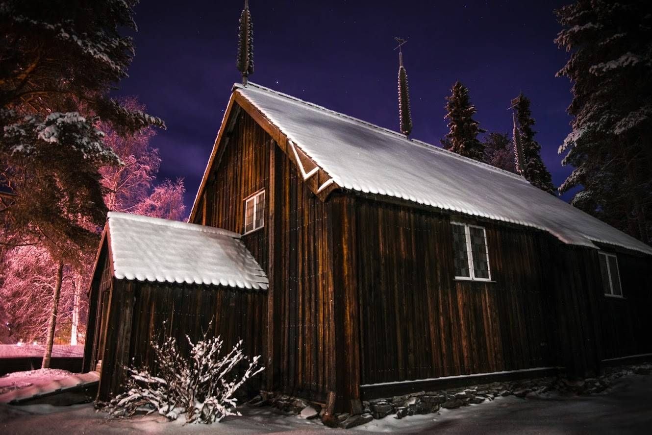 Photo of old wooden church of Sodankylä village at night in winter, Finland.