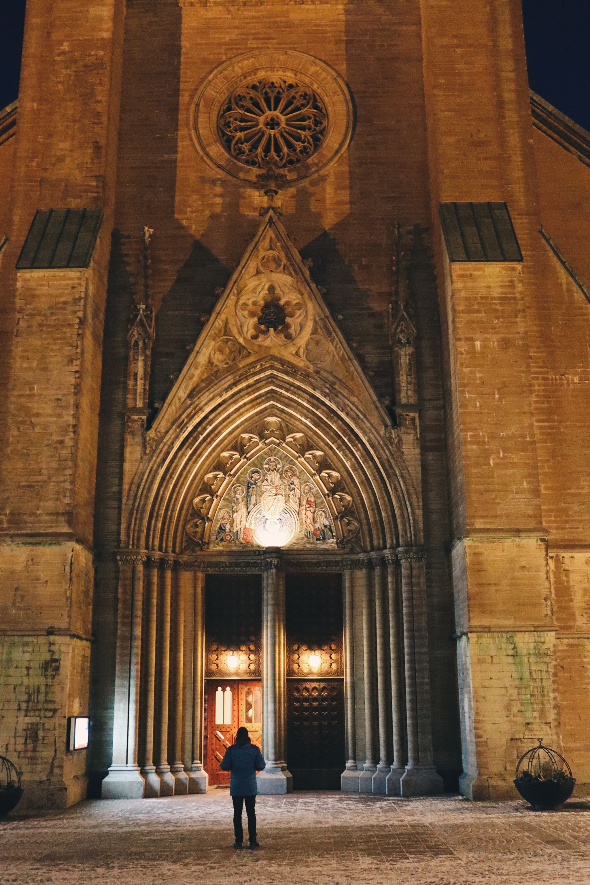 photo of night view of man standing and watching Linköping Cathedral in Östergötland County, Sweden.