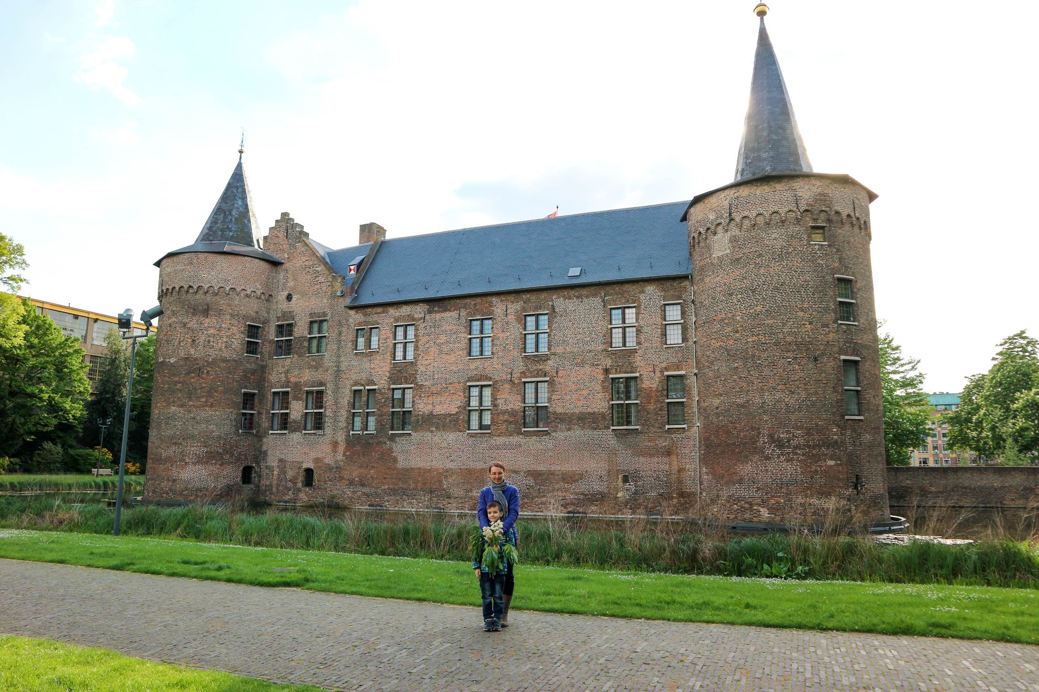 photo of tourist family mother and son posing against beautiful medieval castle Helmond, Netherlands.