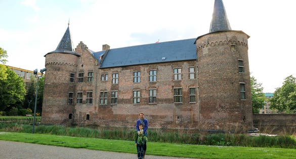 photo of tourist family mother and son posing against beautiful medieval castle Helmond, Netherlands.