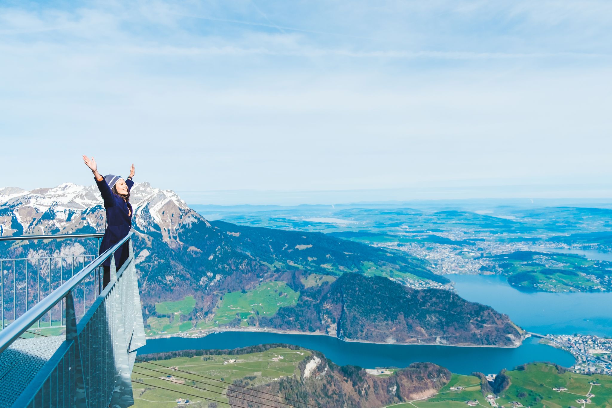 photo of young woman tourist standing with hands up achieving with the snow mountain background, Mt. Stanserhorn in Switzerland.