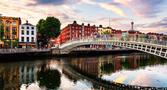Photo of view of famous illuminated Ha Penny Bridge in Dublin, Ireland at sunset.