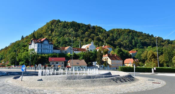 Roundabout with fountain in the middle and Parish of Celje - St. Cecilia at the base of the hill behind in Stajerska, Slovenia