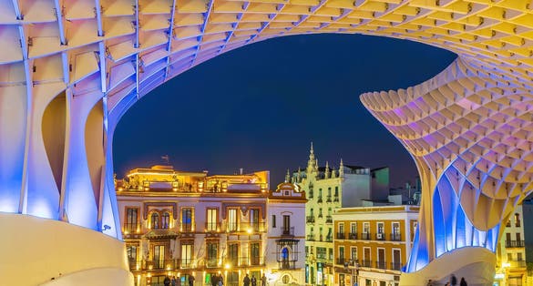 Photo of Metropol Parasol wooden structure with Seville city skyline in the old quarter of Seville in Spain at night.