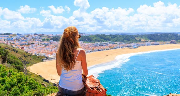 Photo of woman enjoying panoramic view of atlantic ocean, Nazare beach, Algarve in Portugal.