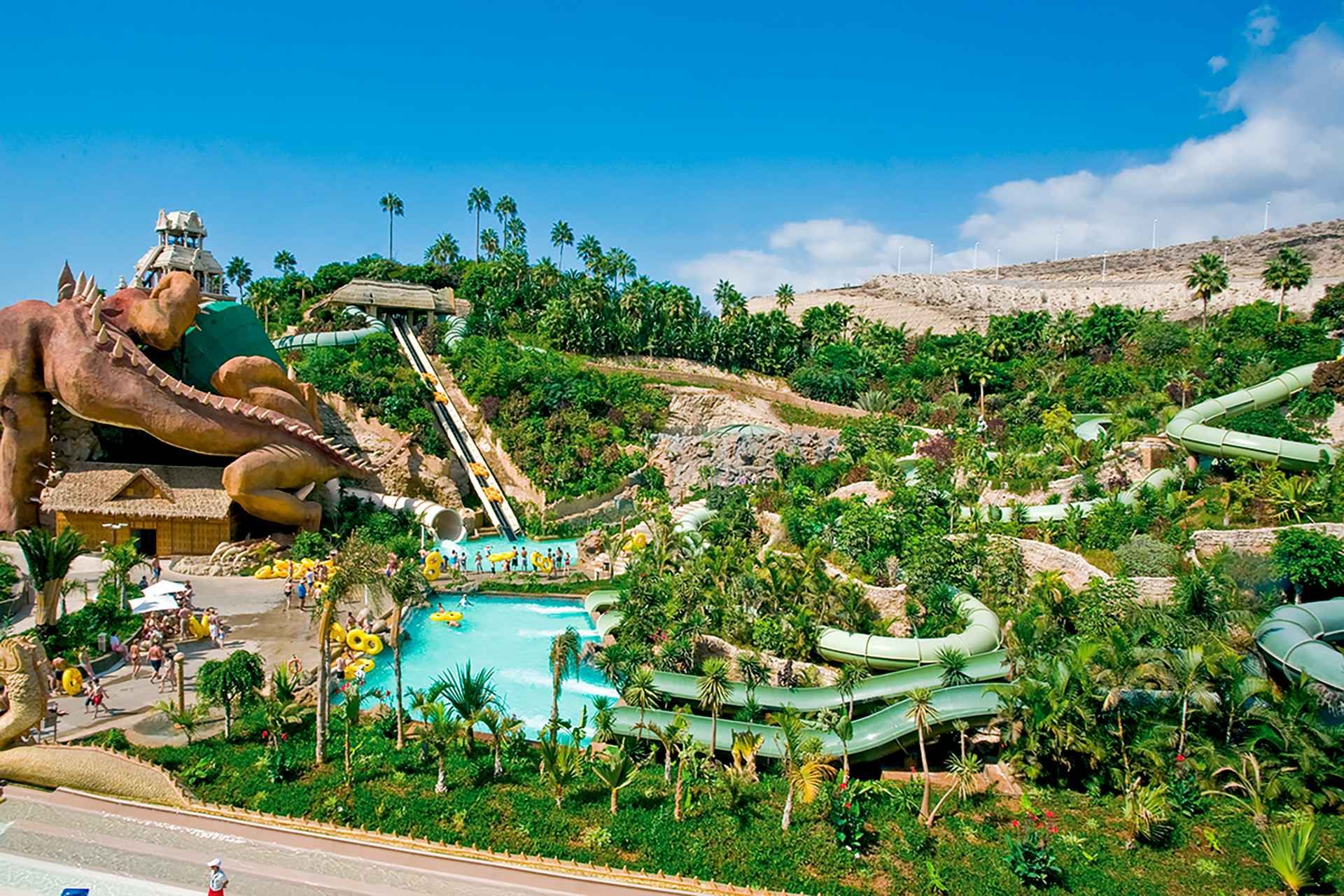 Siam Park in Costa Adeje, Tenerife, features green slides, pools, and a large dragon-like statue under a blue sky..jpg