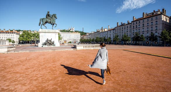 photo of woman walking on the famous Bellecour square with Louis king statue traveling in Lyon city in France.