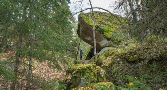 photo of man under large rock Sweden nature in Tiveden national park.