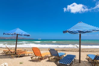 Kalyves beach in the Crete in Greece. Blue umbrella and yellow beach beds on the background of sea.