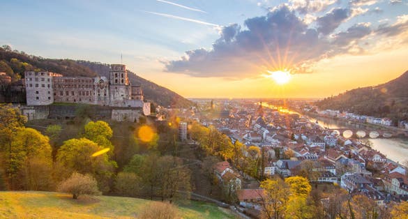 photo of view of View over an old town with a castle or palace rune in the evening at sunset. This place is located in a river valley of the Neckar, surrounded by hills. Heidelberg, Baden-Württemberg, Germany