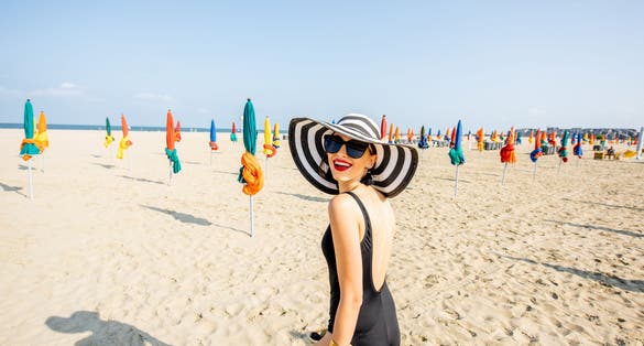 Photo of Woman walking on the beach with colorful umbrellas in Deauville, famous french resort in Normandy