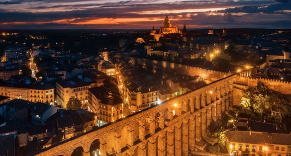 photo of view of Segovia Cathedral and aqueduct aerial view at night in Spain.