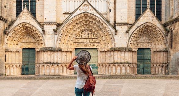 Woman tourist looking at cathedral in Poitiers- France, Vienne department ( Notre Dame la Grande)