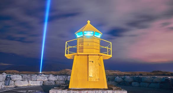 photo of view of Lighthouse and Imagine Peace Tower on Videy island in Reykjavik at night, Reykjavík, Iceland.