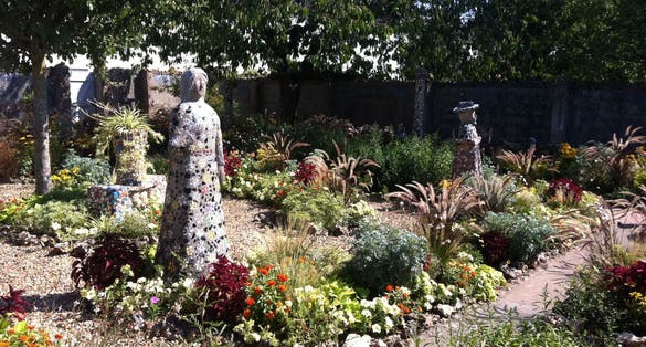 photo of flowers garden and mosaic statues at Maison Picassiette in Chartres, France.