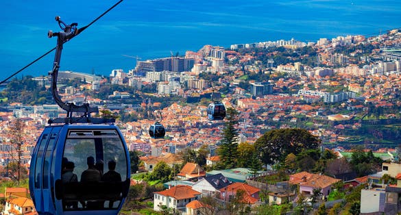 Photo of erial view of Funchal with traditional cable car above the city.