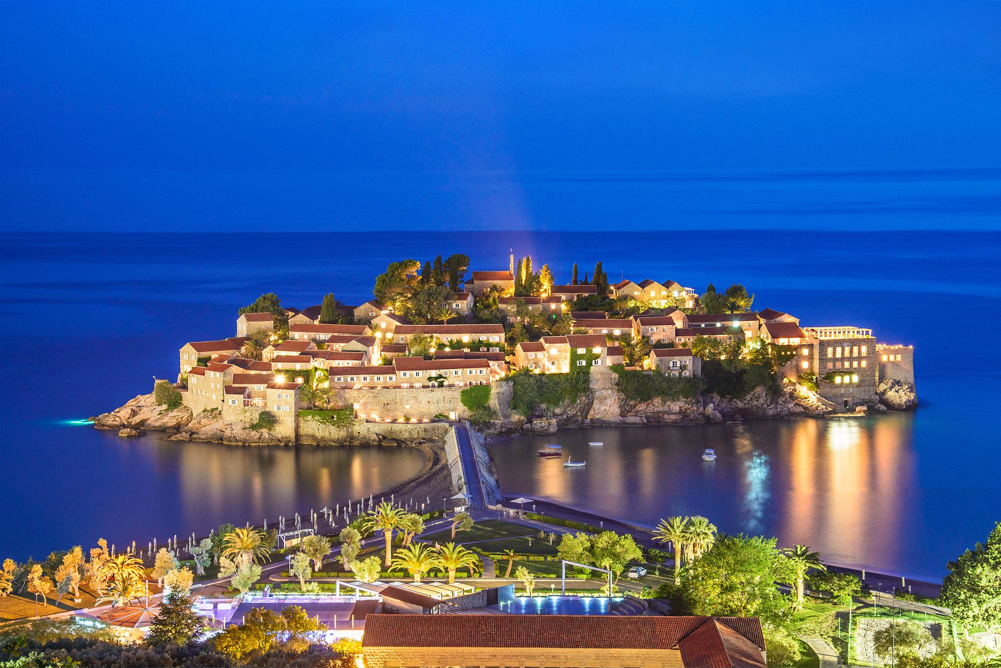 Photo of Night Sveti Stefan view with lights in windows, small islet and hotel resort in Montenegro.