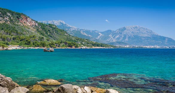 Photo of Montenegro coast seascape with perfect blue water with mountains around, blue sky near Bar town.