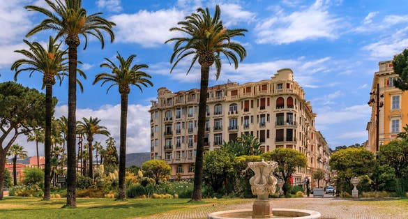 photo of Triton Fountain at Albert I Garden its ancient Greek statue and historical monument with Mediterranean house facades in Nice, France.