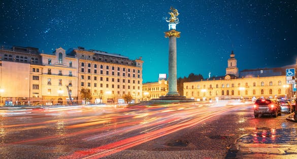 photo of Amazing Bold Bright Blue Starry Sky Gradient Above Liberty Monument Depicting St George Slaying the Dragon and Tbilisi City Hall in Freedom Square in City Center in Georgia.