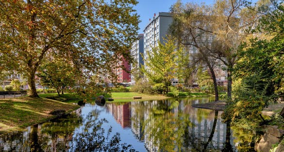 Photo of view of buildings in the city of Vigo, Spain, as seen from lake in Castrelos Park.