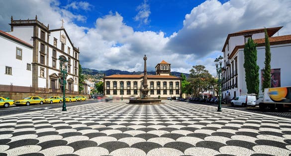 Beautiful cityscape of the townsquare Praca do Municipio in Funchal, Madeira, with the Church of St. John the Evangelist and the city hall, on a summer day with blue sky and clouds