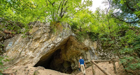 photo of view of People visiting Istállós-kői Cave at summer - Mouth of a cave about 60 metres long and 17 metres high, Szilvásvárad, Hungary.